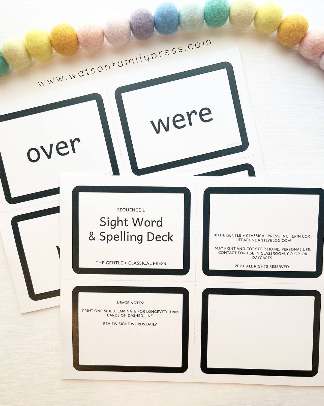 A printed card deck titled 'Sequence 1 Sight Word & Spelling Deck' photographed on a light surface with colorful pom-poms around the edges.