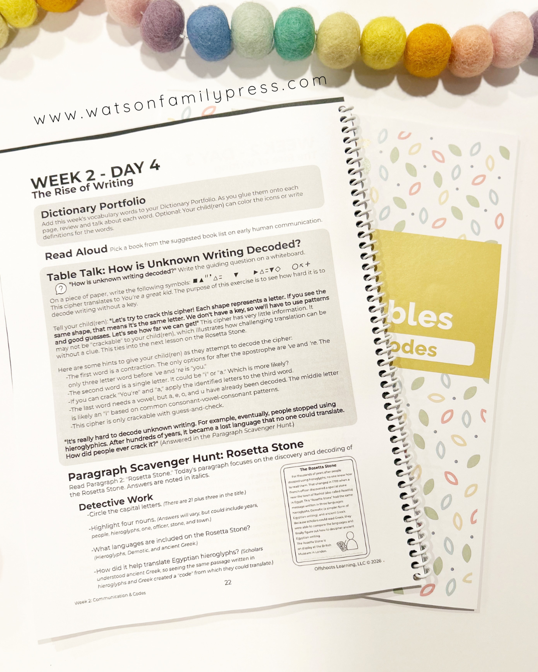 Open educational workbook with text and a colorful bead necklace on a white surface