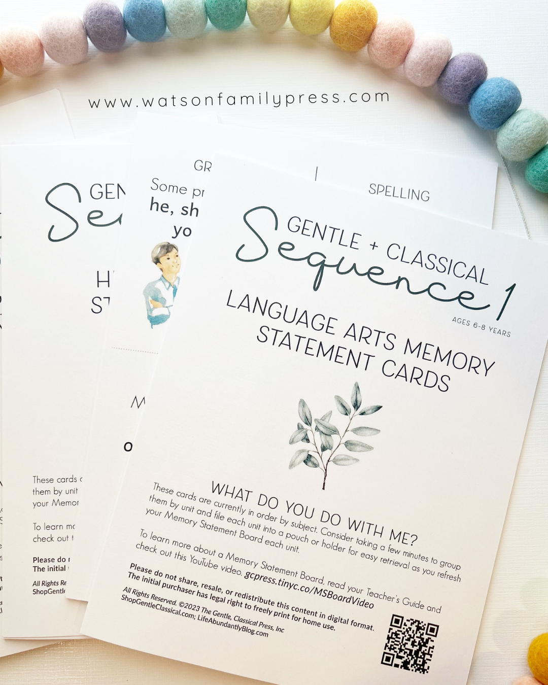 A printed card deck titled 'Gentle + Classical Sequence 1 Memory Statement Cards' for 3-part Montessori cards, featuring partial  illustrations on white cards, photographed on a light surface with colorful pom-poms around the edges.