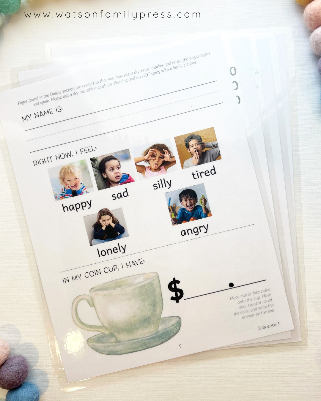 Laminated student activity sheets styled on a light surface with colorful pom-pom beads around it.