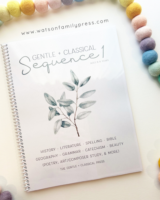 A spiral-bound educational curriculum booklet titled 'Gentle + Classical Sequence 1' with a branch illustration on the cover, photographed on a light surface with colorful felt pom-poms around it.