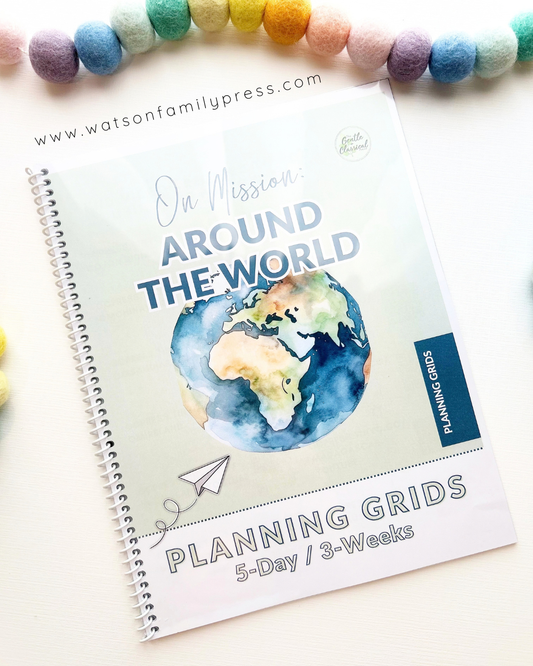 A spiral-bound educational curriculum booklet titled 'On Mission Around the World' with an earth illustration on the cover, photographed on a light surface with colorful felt pom-poms around it.