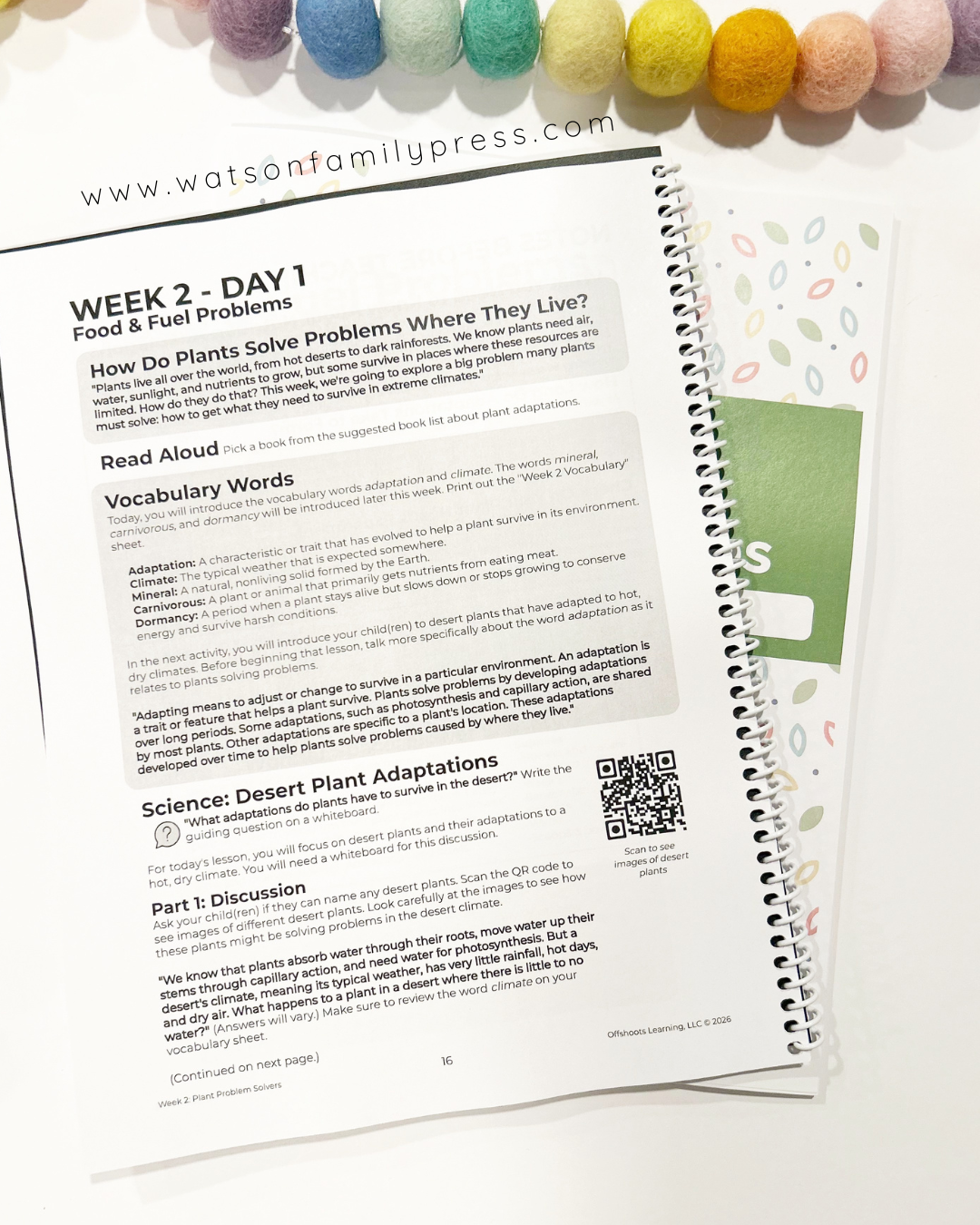 Spiral-bound educational book with text and a QR code on a white background