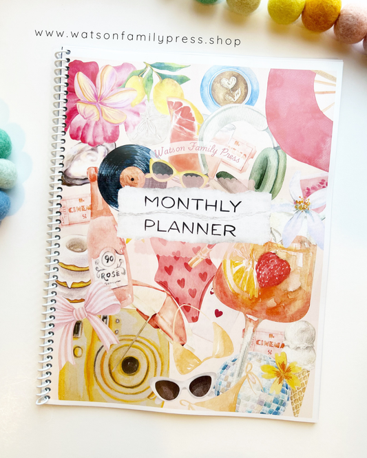 Spiral bound monthly planner with colorful pink collage design on a white surface